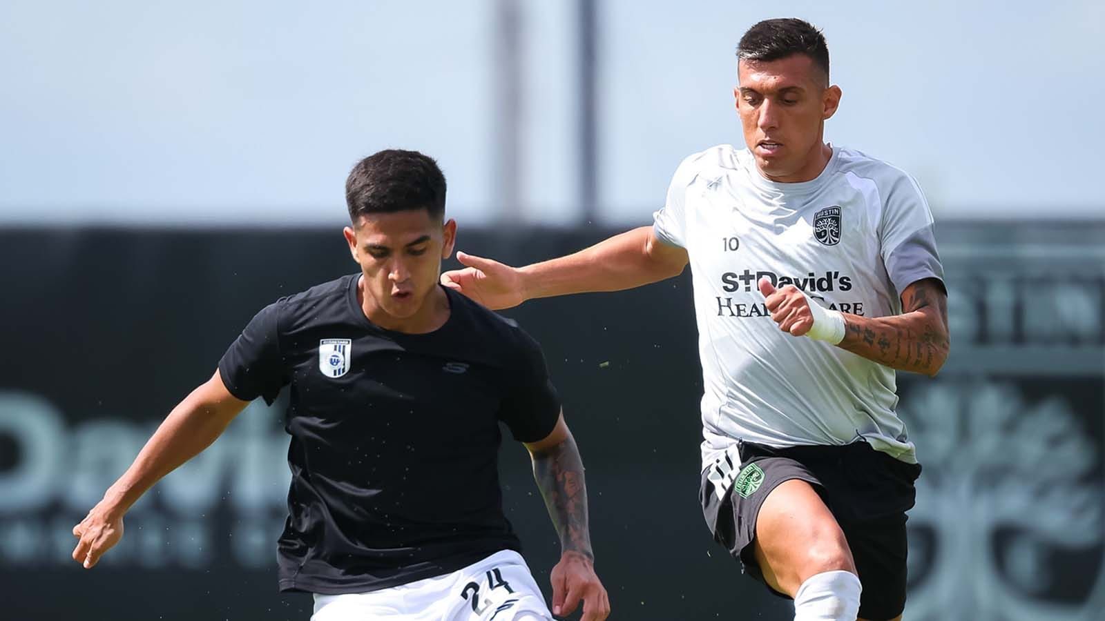 Austin FC's Myrto Uzuni running alongside a Querétaro FC player, putting a hand on his shoulder