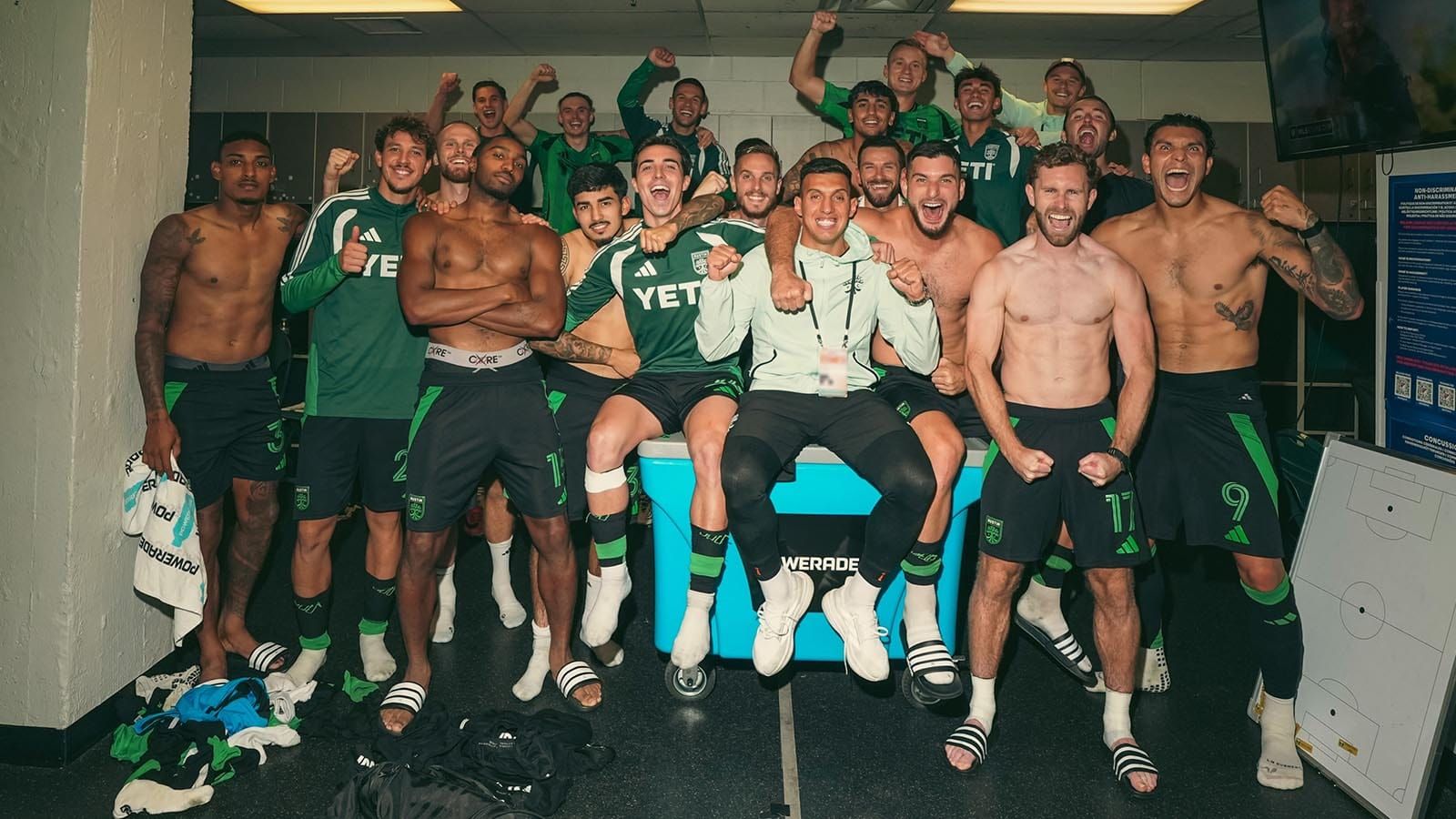 Austin FC pictured celebrating a win in Portland with its now-trademark road win victory photo, featuring multiple shirtless players exulting