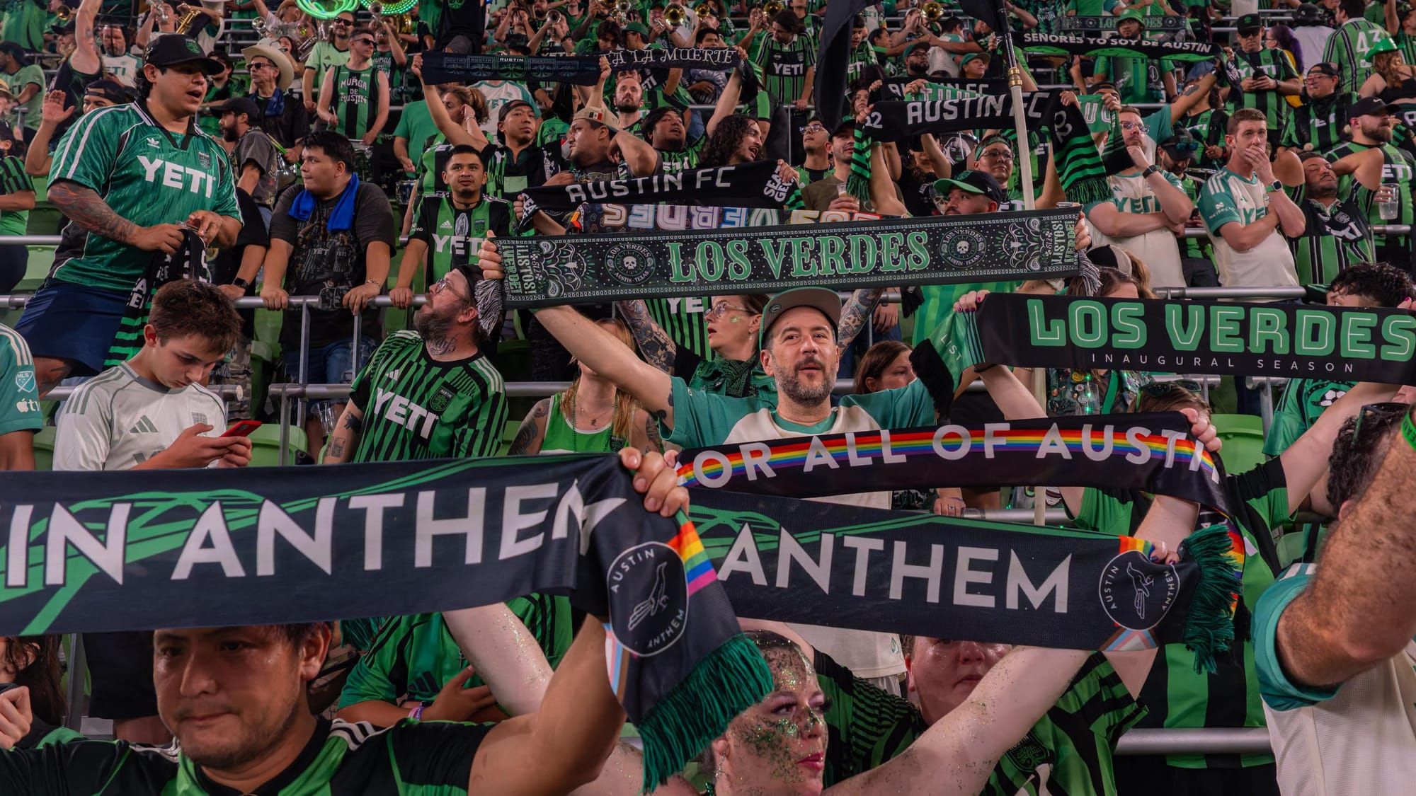 Austin FC supporters holding scarves repping Austin Anthem and Los Verdes