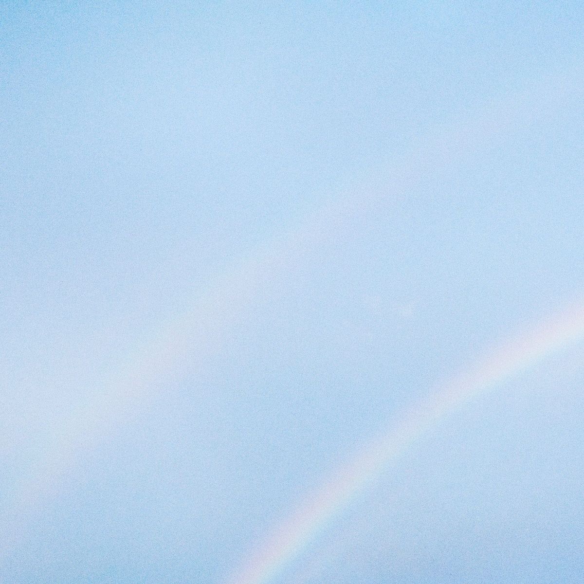 NEVER ENOUGH album cover — light rainbow on a blue sky