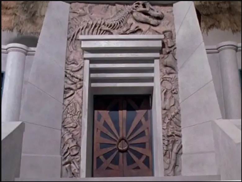 A close-up of the entrance to the visitors' center, showing the trapezoidal buttresses flanking the three elements of the entryway: (1) the doors, (2) the lintel (or false architrave), and (3) the bas-relief.