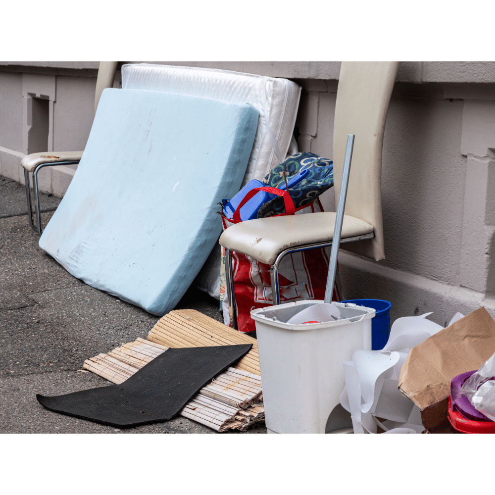 Mattress and household junk arranged curbside for removal
