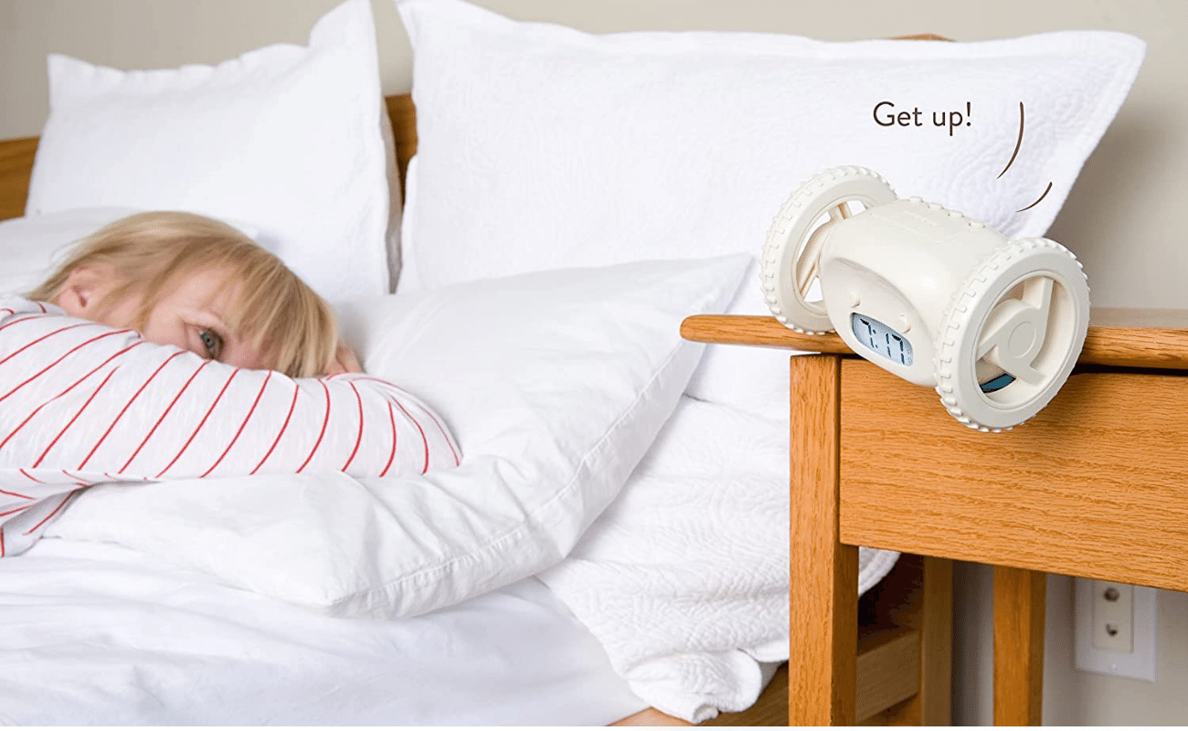 clocky alarm clock jumping off nightstand while person sleeps in bed (C: Clocky/Amazon)
