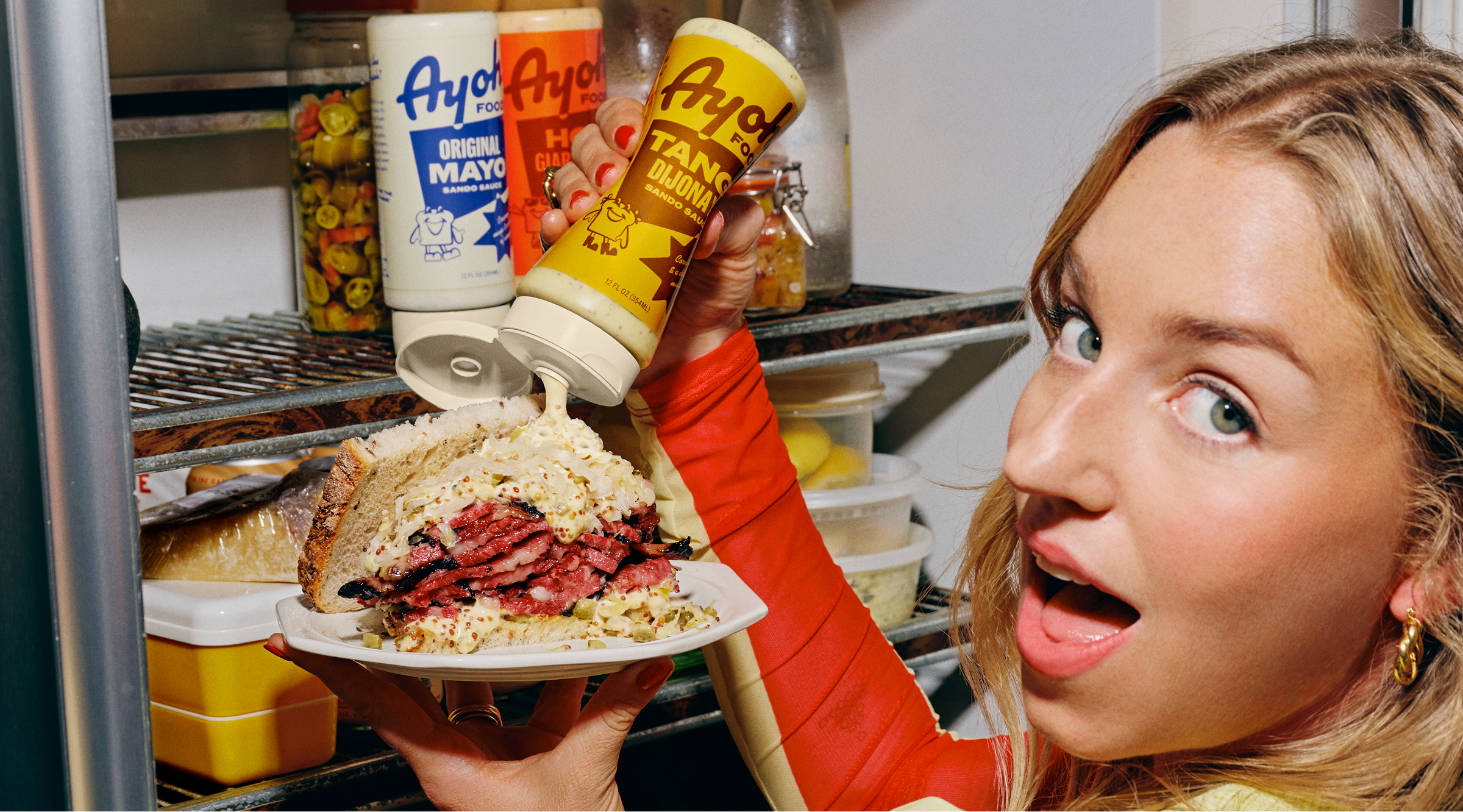 Readymag blog: A photo of a mayo brand Ayoh! founder squeezing mayo onto a sandwich. The branding is by CENTER