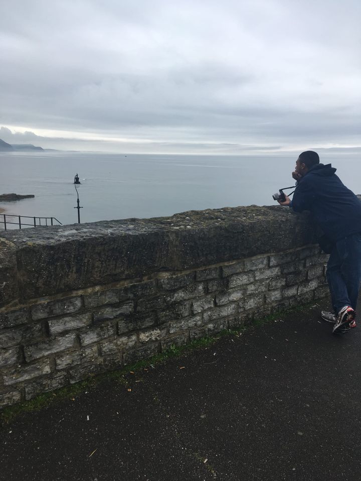 Vaughn Hunt leaning against a weathered cement wall, staring out to sea. 