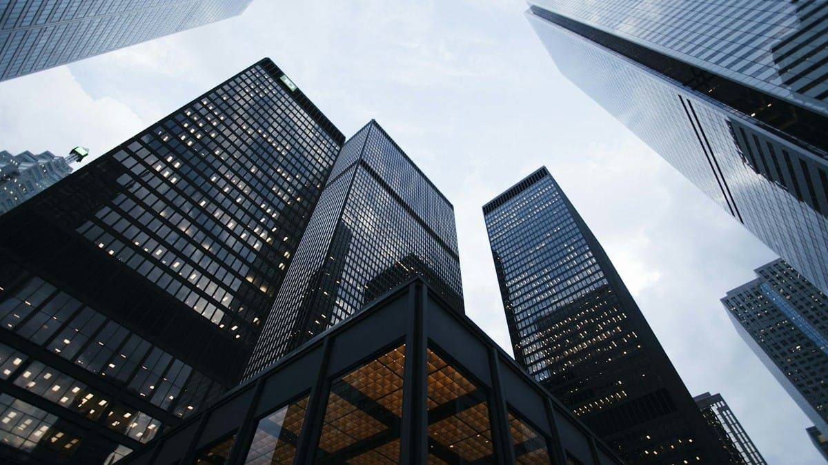 Looking up at dark glass skyscrapers against a pale sky, no text overlay