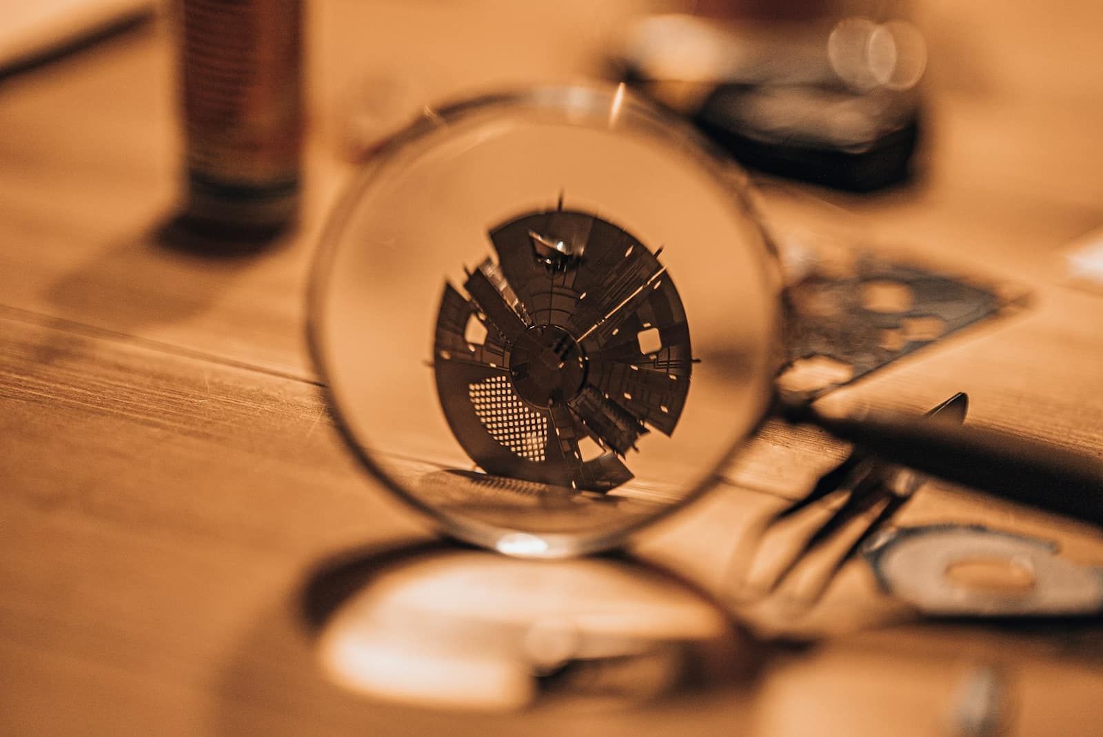 Close-up of magnifying glass inspecting electronic circuit board representing online scam detection and financial fraud prevention strategies by Dollar Vigil.