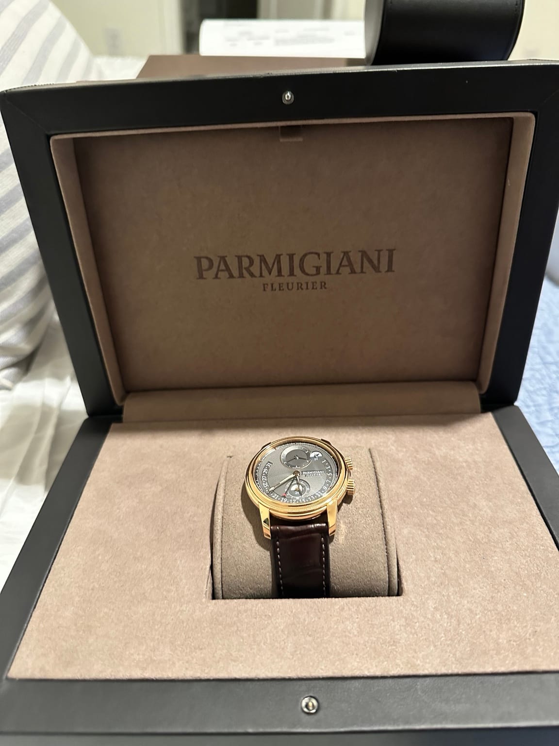 The rose-gold Parmigiani Fleurier Toric resting on its cushion inside the open presentation box.