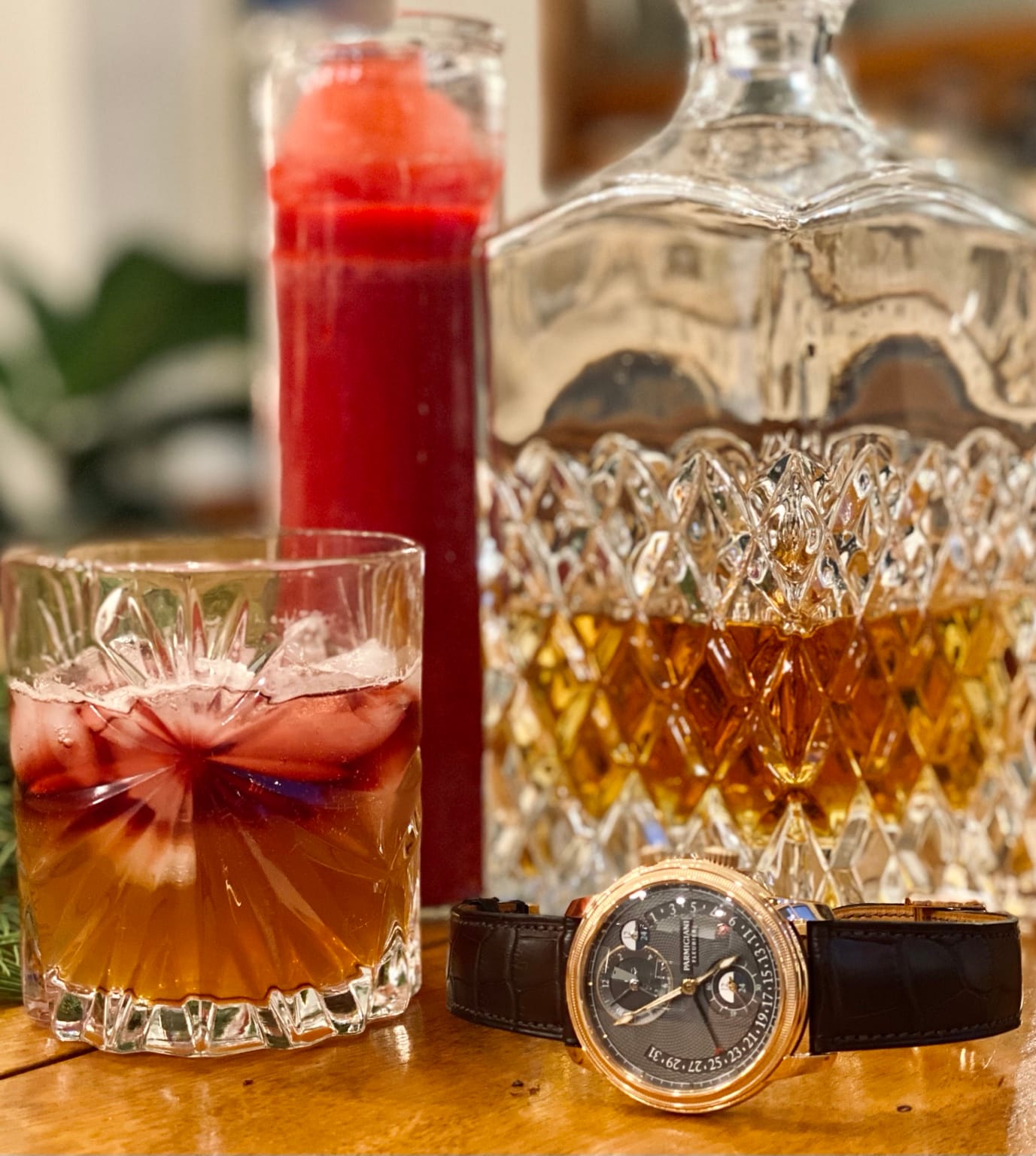 A rose-gold Parmigiani Fleurier Toric with a dark guilloché dial beside a cocktail and crystal decanter.