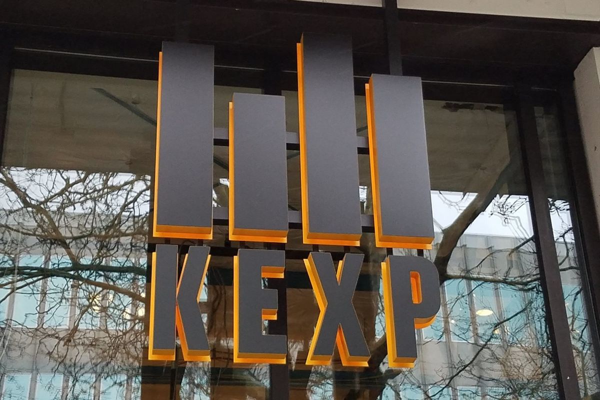 Backlit gray block letters spelling KEXP on a glass storefront