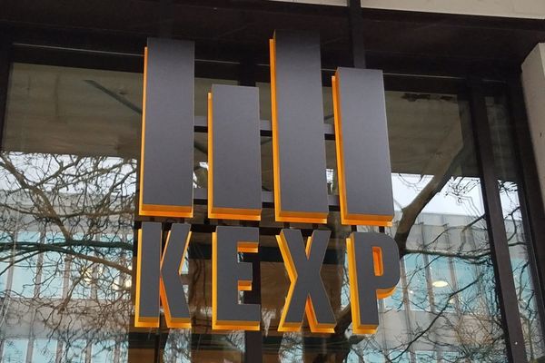 Backlit gray block letters spelling KEXP on a glass storefront