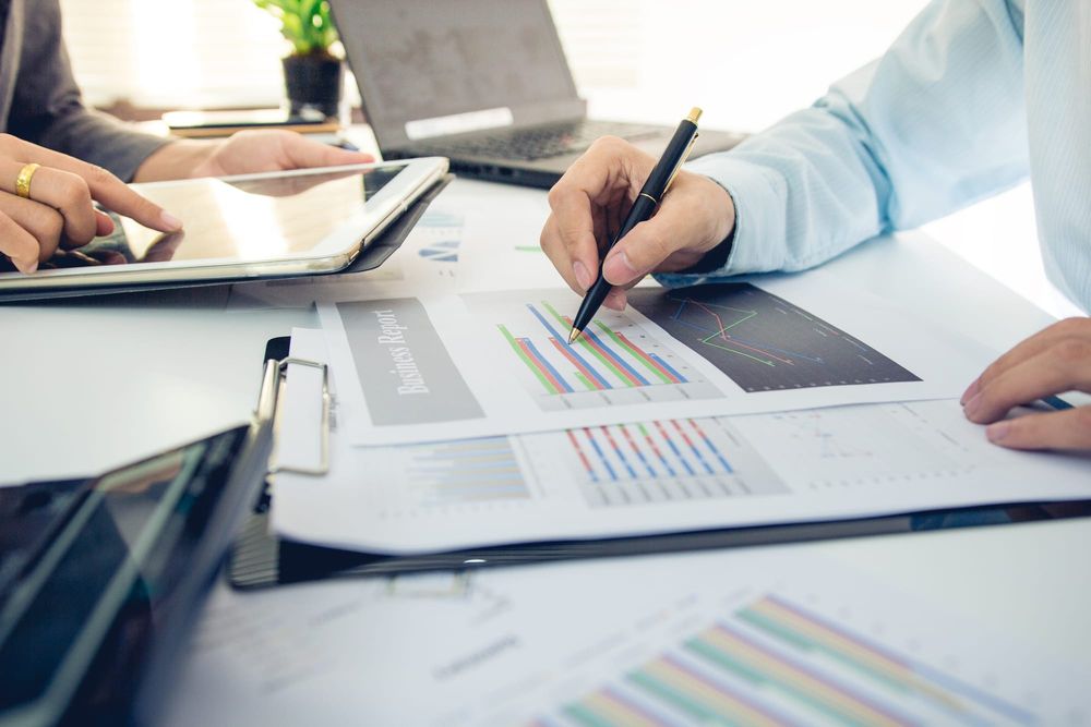 Executive reviewing printed financial charts and a tablet while comparing office buy-versus-lease costs