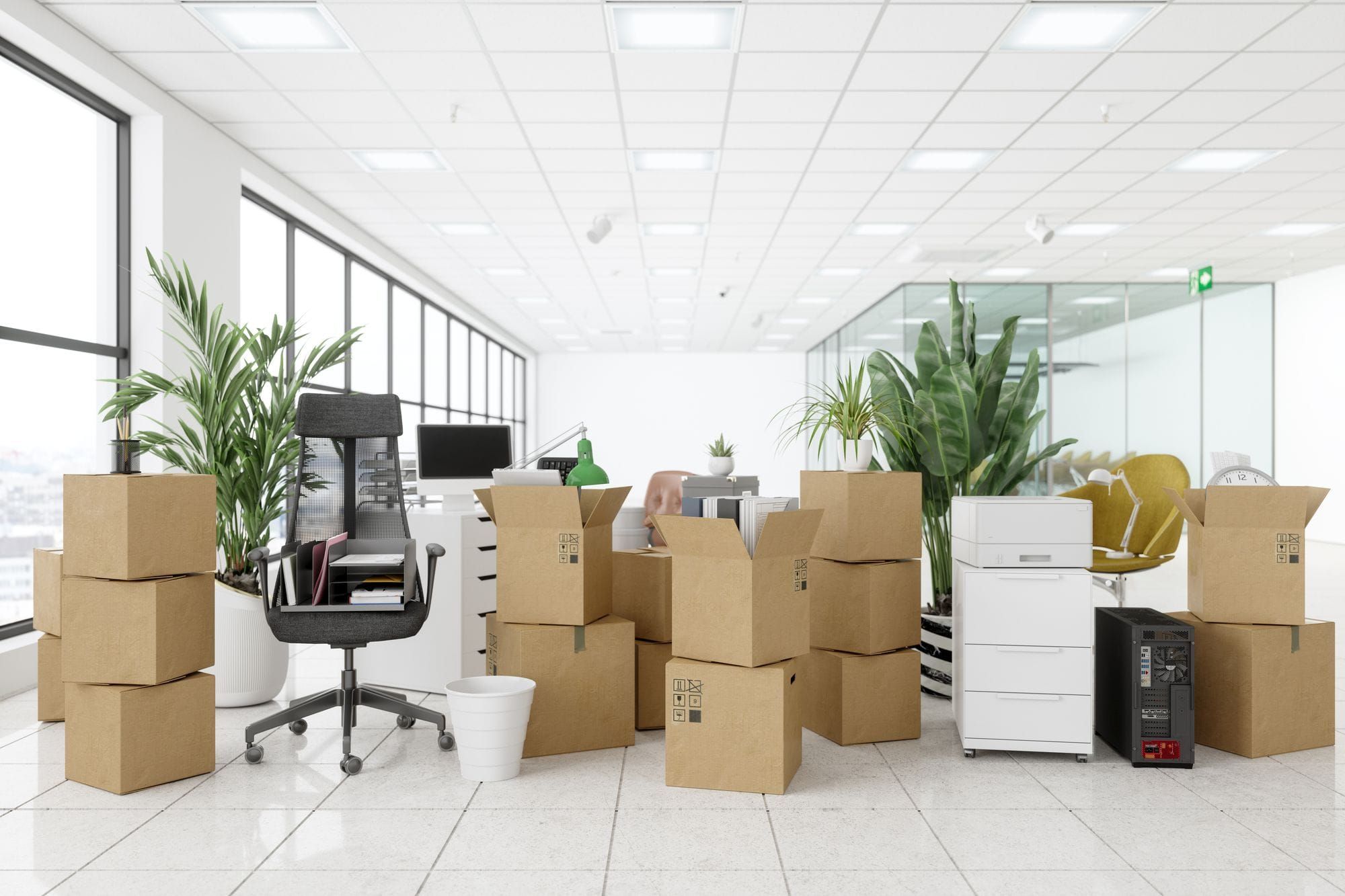 A modern office mid-move, with packed cardboard moving boxes around a desk, office chair, and filing cabinet