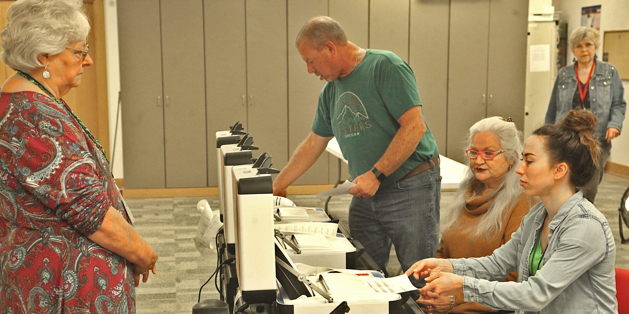 man standing with row of three voting machines