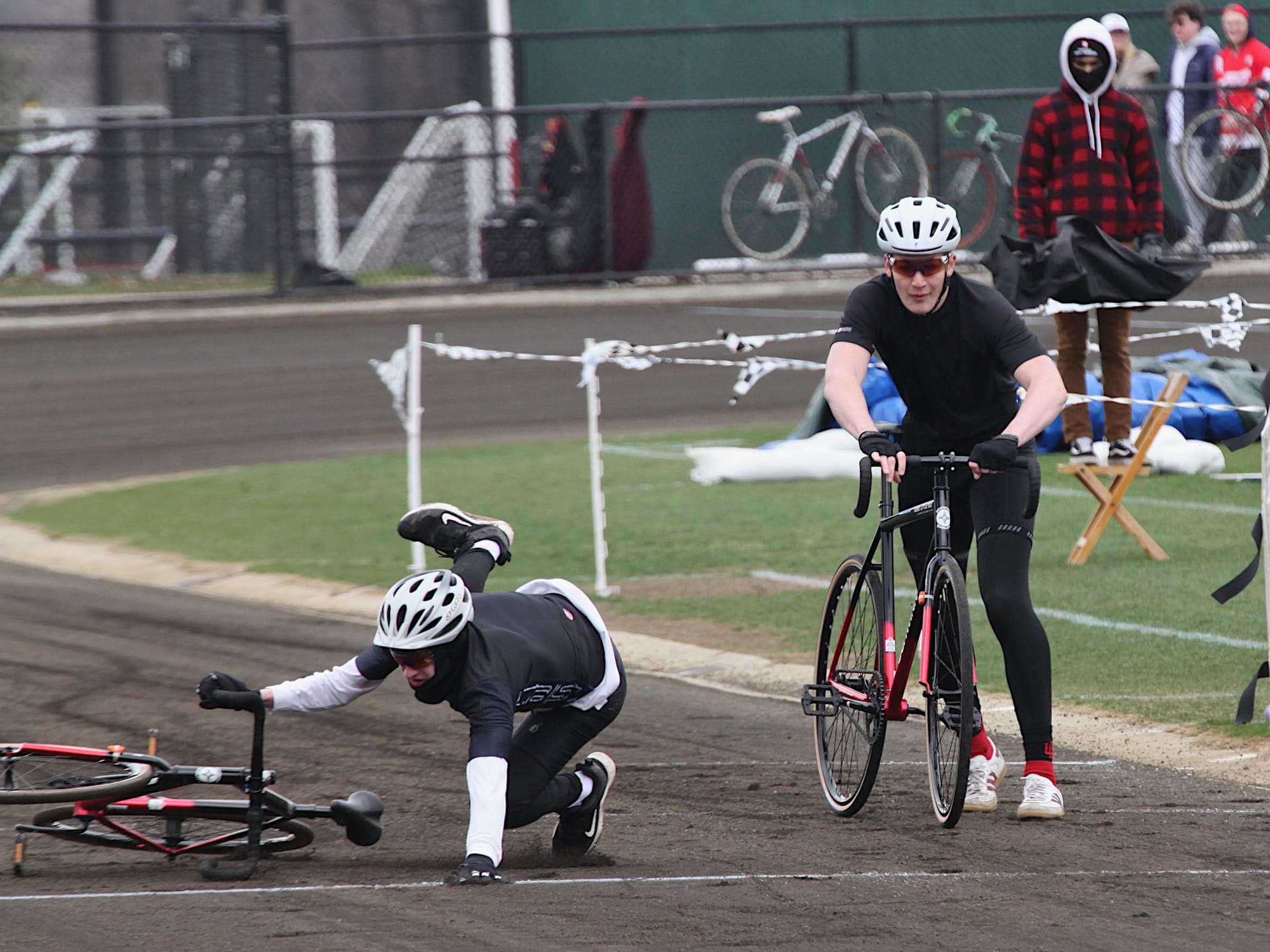 riders exchanging bicycles in qualifications for a race one of them falling to the ground