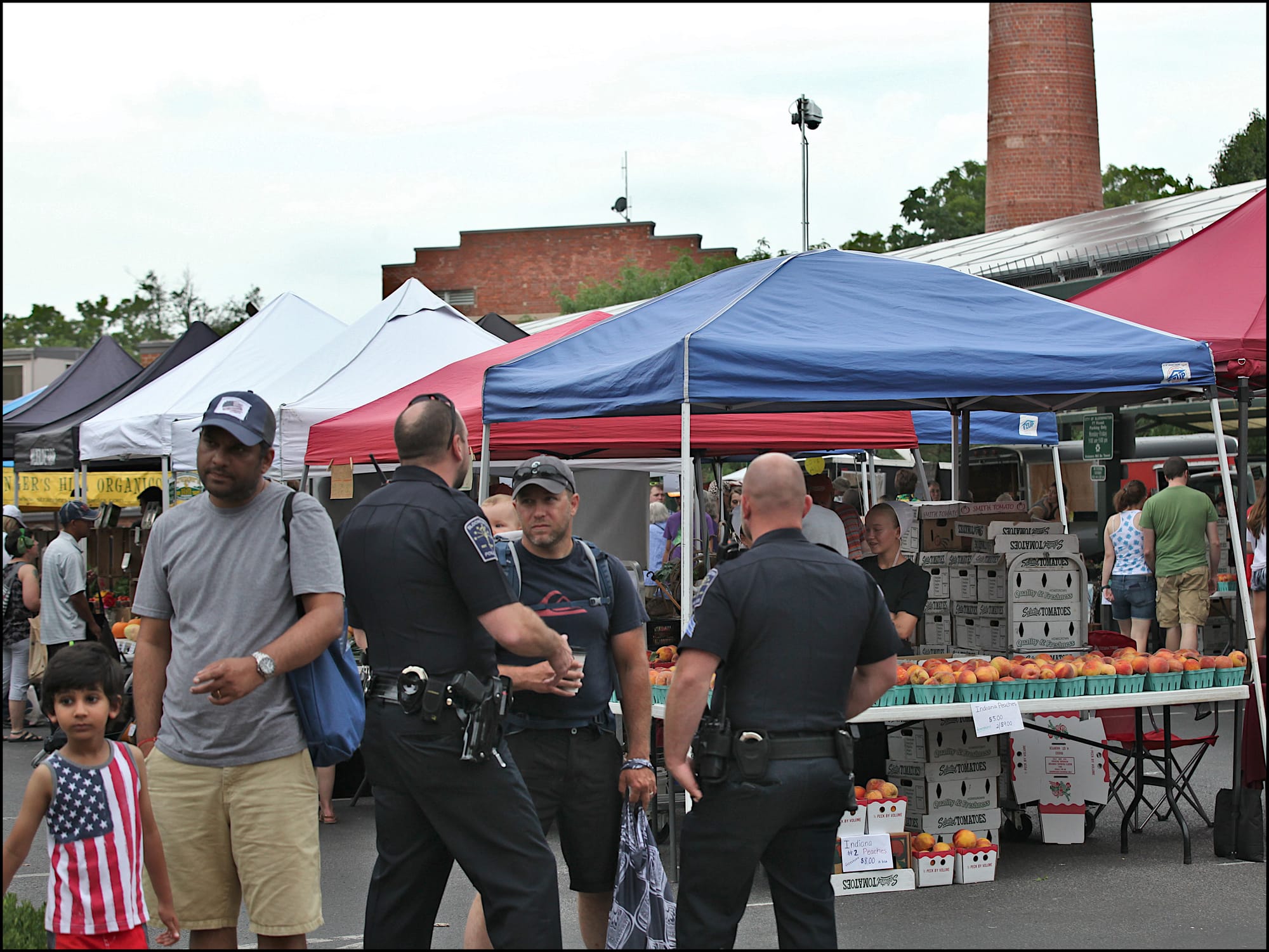 File photo showing two police officers talking to farmers market patrons in August 2019