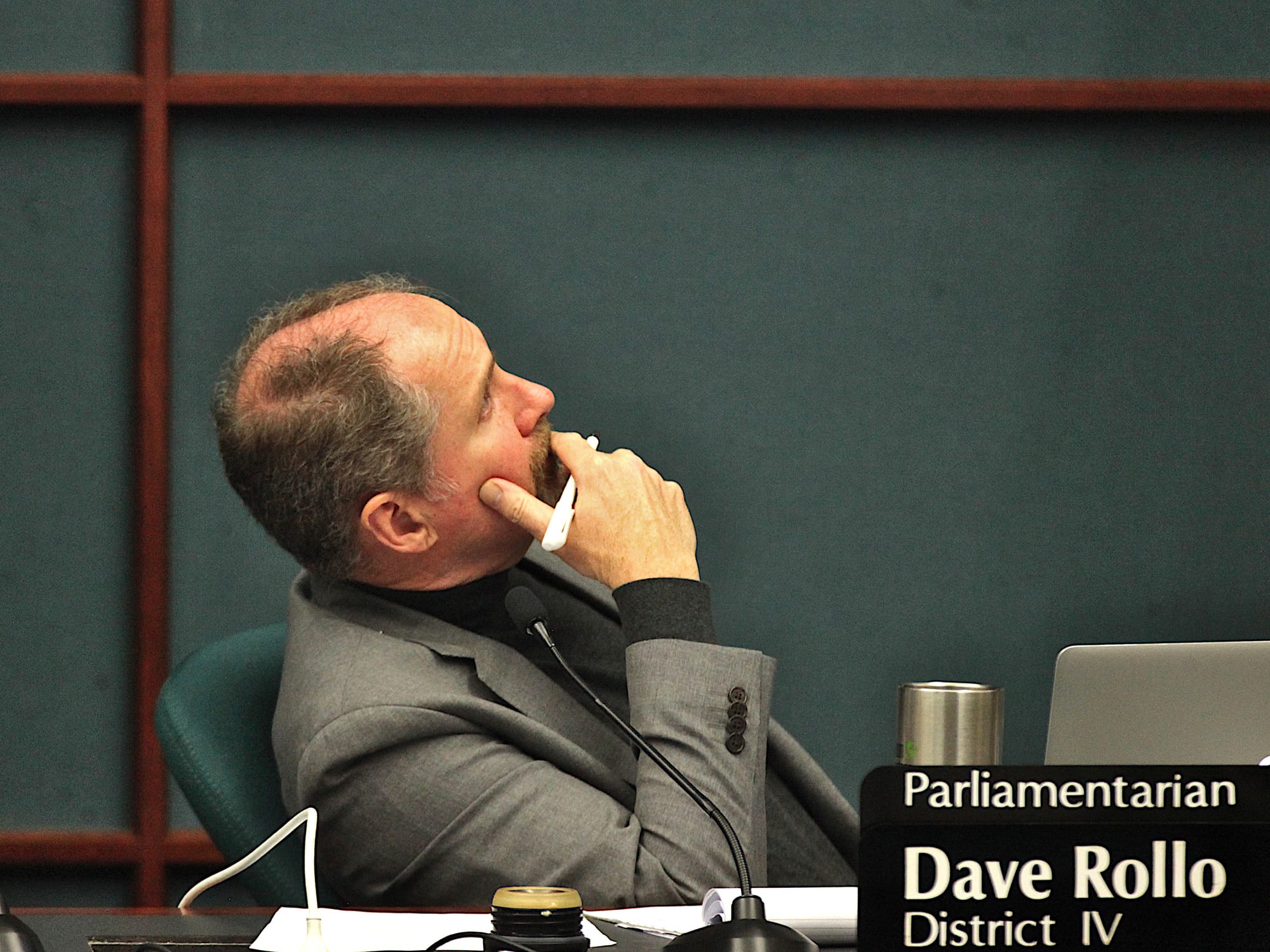man sitting at council dais looking up and to his left