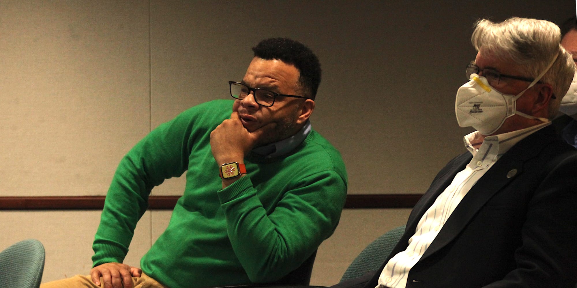 two men sitting in chairs looking to the left