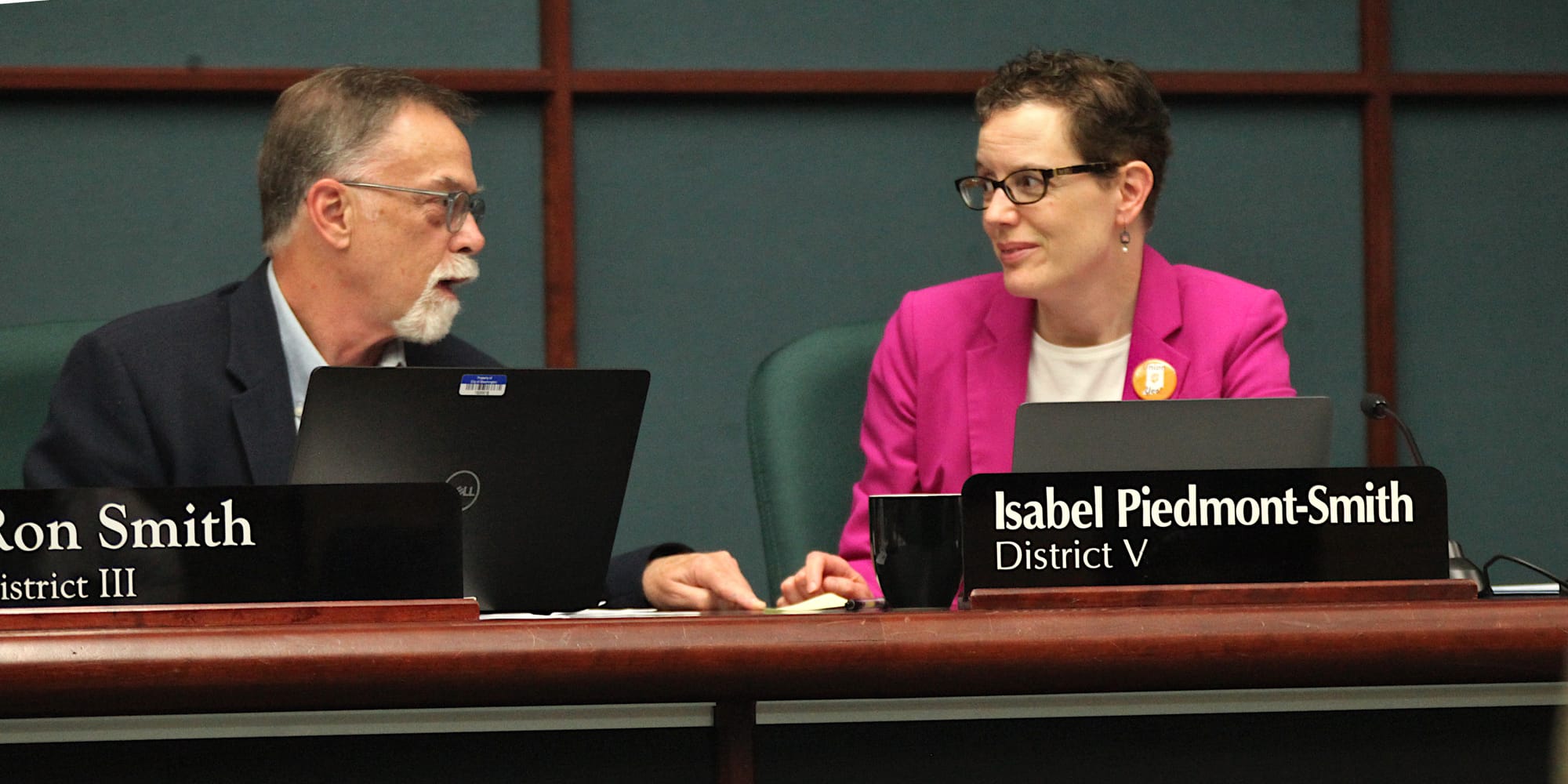man on left and woman on right with their hands resting on the city council dais