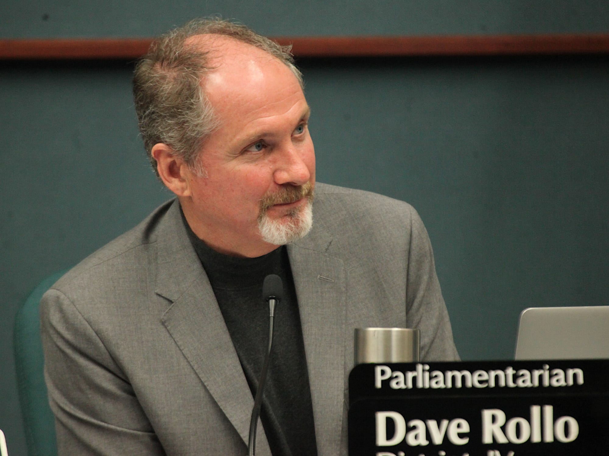 man sitting at city council dais smiling