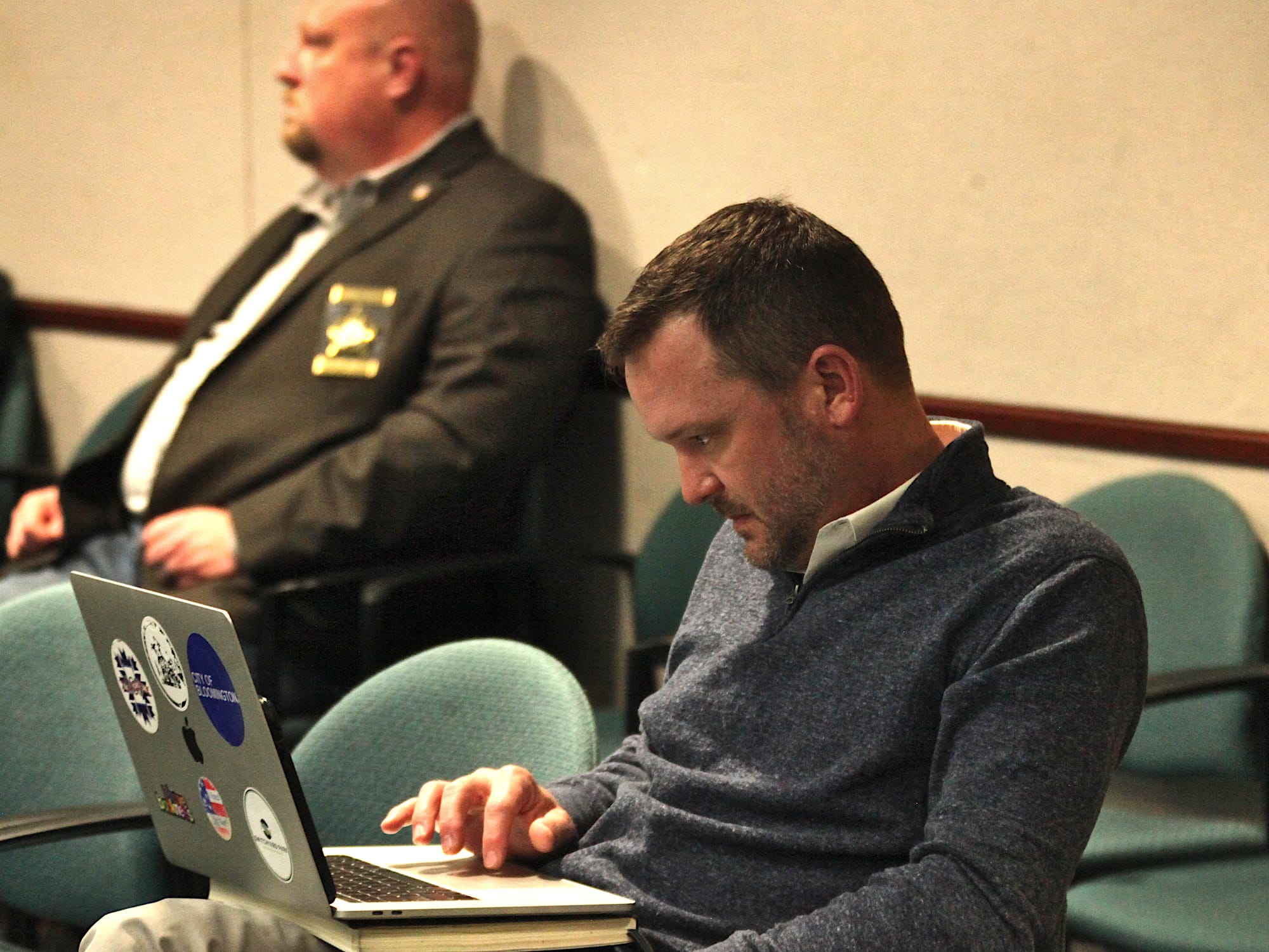 man seated in chair looking at his laptop computer