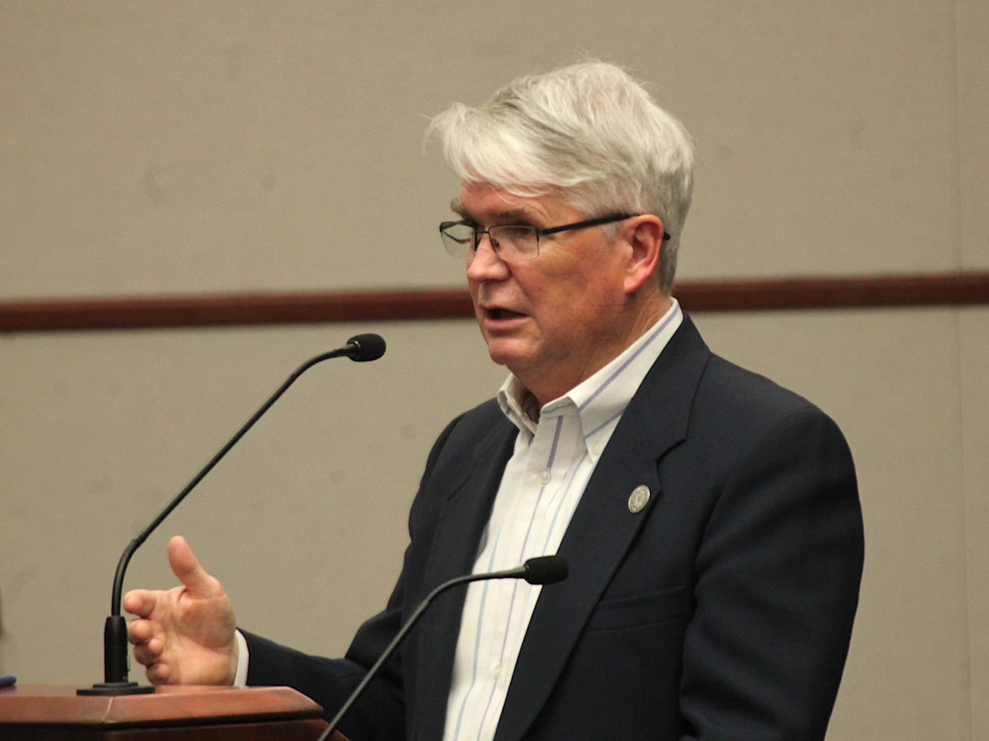man standing at podium and mic gesturing with his right hand