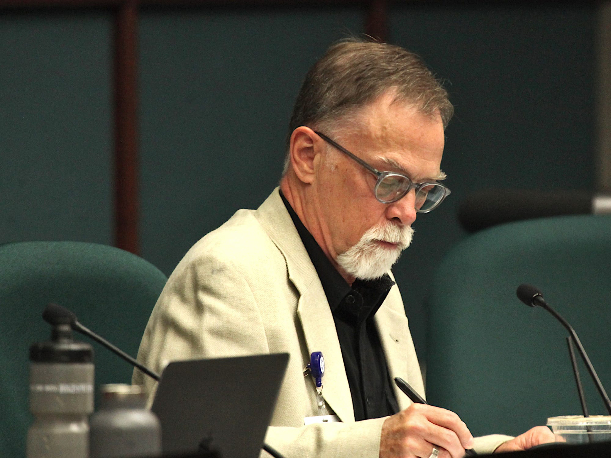 man seated at dais writing