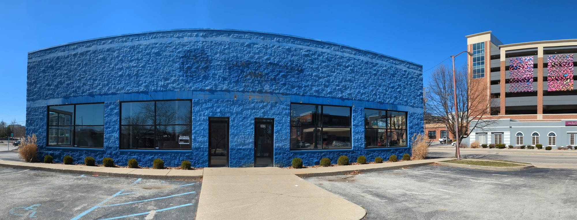 exterior of a former NAPA building at 3rd and Walnut with parking garage and its colorful tile artwork in the background