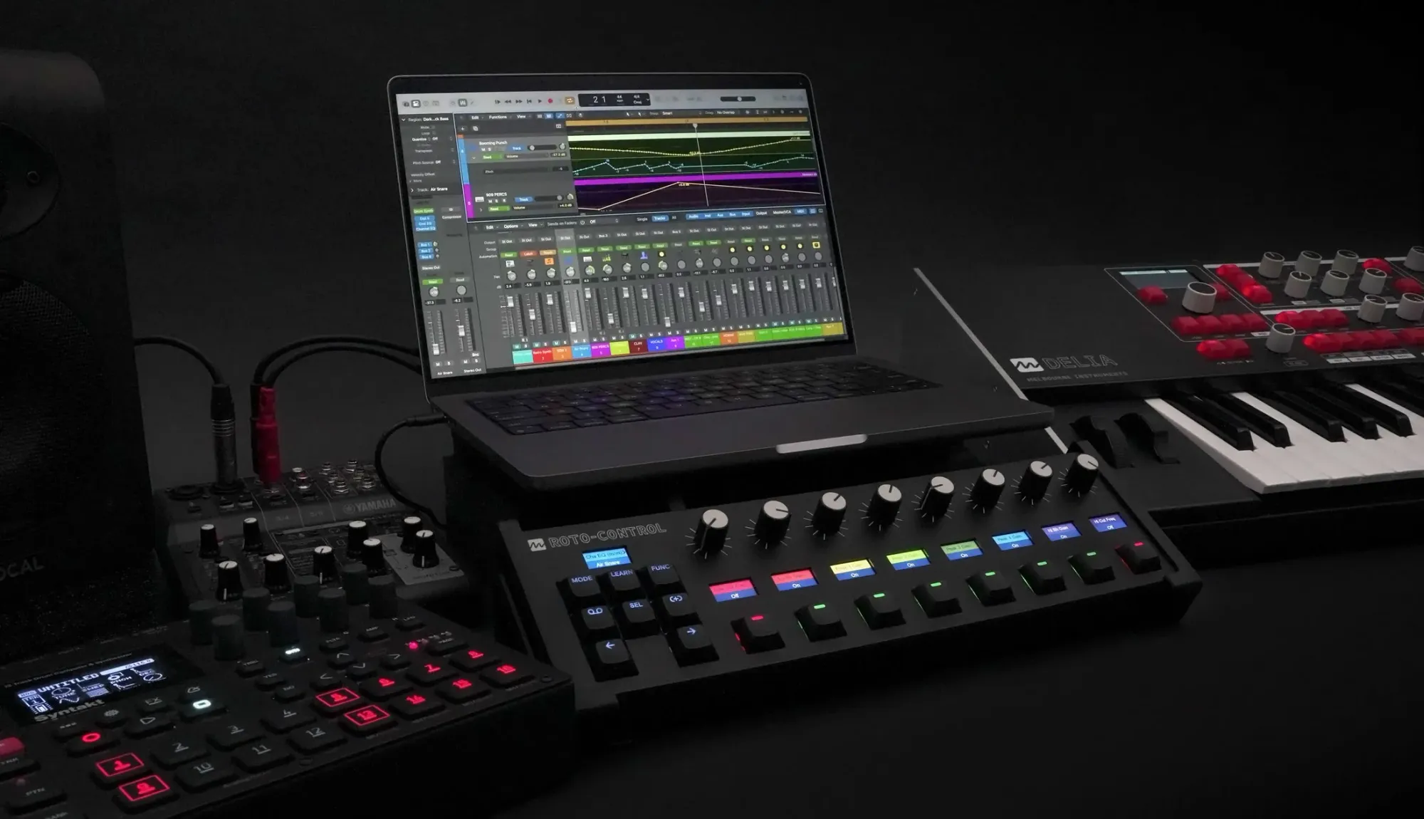 ROTO-CONTROL beside a Mac running an English Logic Pro mixer