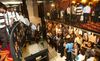People line up on and below the stairs leading to a hiring fair; next to the stairs is a wall of mirrors that reflects some of their images back