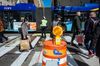 People cross a New York City crosswalk as a bus passes by behind them
