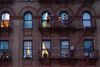 Residents of a Bronx apartment building look out at the street from their fire escapes