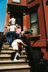 People paint the sides of a brownstone building