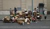 People walk by a curb piled high with cardboard boxes