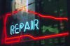 A red neon sign in the shape of a dress shoe with the word "repair" written in light blue neon within it