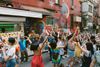 A large group of people dancing on the street in front of a mural
