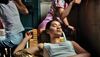 A woman lounges with her eyes closed on a lawn chair inside a restaurant with two other figures in the background