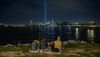 4 people look at the New York skyline at night over the water
