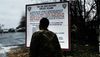 Back shot of a person facing a sign entitled "you are now entering Rikers Island"