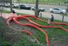 A toddler's father walks with her next to a large sculpture of a squid at a park to meet her mother on the other side