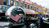 A giant disco ball is displayed on a a parade float next to an American flag on a block in Sunset Park, Brooklyn