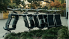 Several office chairs sit outside an office building, with some stacked upside down on top of others