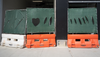 Three water barriers holding up chain link construction panels with the shape of a heart cut out of the privacy screening