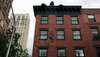 A halloween display on the side of a New York City apartment depicts Spider-Man scaling a web on the front of the building, with King Kong peeking out from the roof