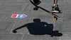 A shadow of a figure doing a skateboard trick above a Vote NYC sticker on the ground pointing toward a polling place