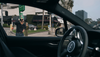 Two pedestrians peer into the window of a driverless Waymo Robotaxi stopped at a light