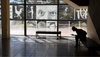 Silhouetted person on a bench looks at a phone beside an etched glass wall