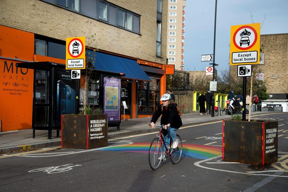 A woman rides a bike between two planters on a street in a Low-Traffic Neighborhood in London