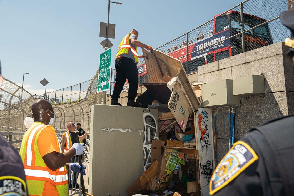 Sanitation workers and NYPD clear out a homeless encampment at the base of Manhattan Bridge
