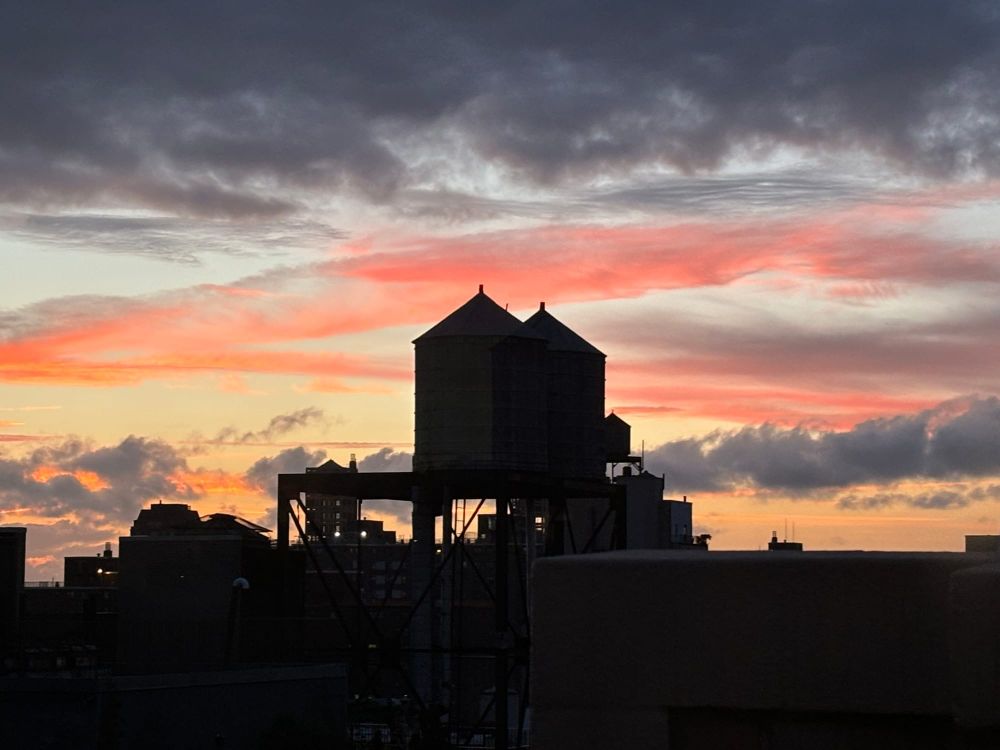 Water towers silhouetted against a red and orange sunset sky